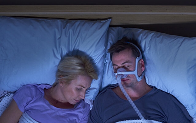 schlafendes Paar mit Herrn, der eine CPAP-Maske n20 trägt