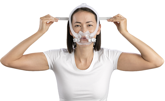 Femme mettant son masque facial ResMed de traitement CPAP