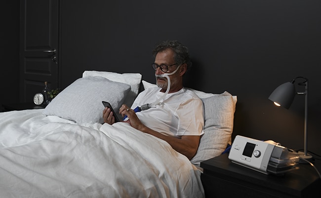 Kopdierter Patient im Bett mit LUMIS HFT-Beatmungsgerät