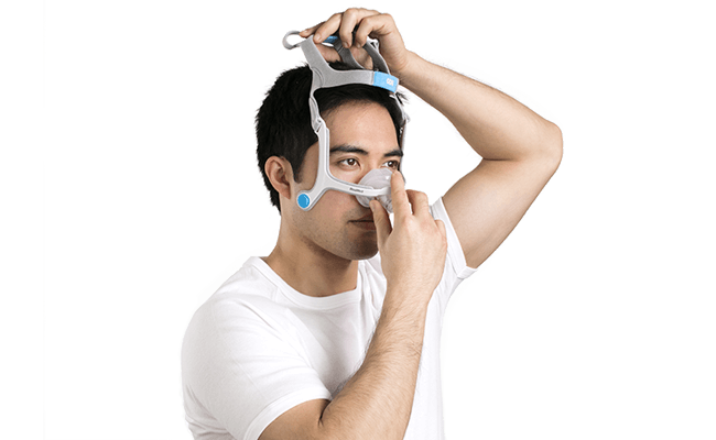 Mann, der seine ResMed-Nasenmaske für CPAP und Beatmung aufsetzt
